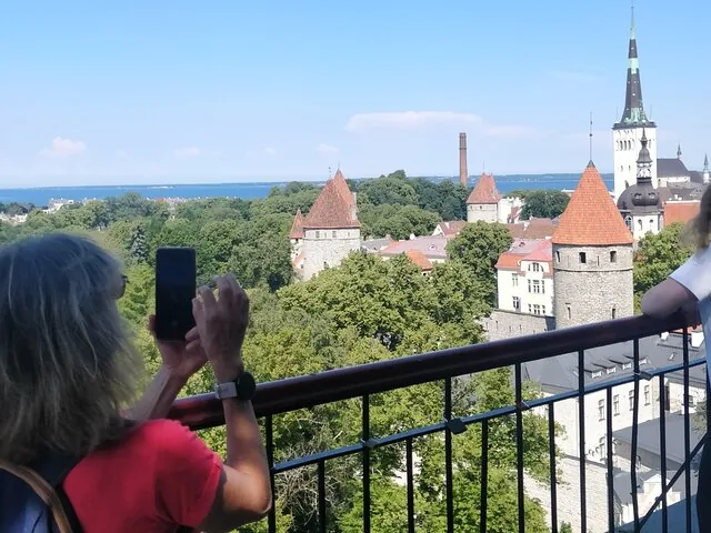 Person taking a photo of a cityscape with medieval towers.